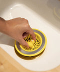 Hand placing Quack Duck Kitchen Sink Strainer Basket Fits All Standard Sinks 4 And A Half Inch Stainless Steel Drain Cover in sink.
