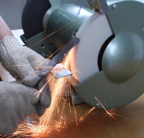 Hands using Heavy Duty 6 Inch Bench Grinder Wheels 80 Grit White Aluminum Oxide Vitrified Ceramic Stones for sharpening.
