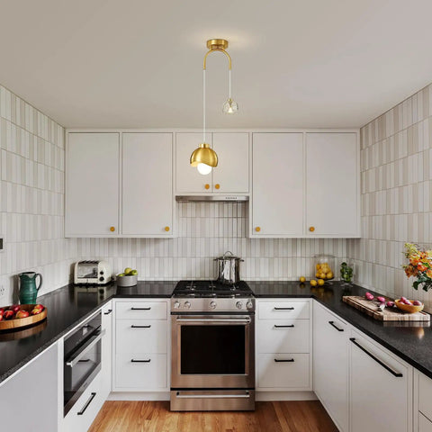 IPEDWO 2-Light Modern Gold Pendant Lights, Light Fixture for Kitchen Island over a stylish black countertop in a contemporary kitchen.