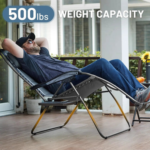 Man relaxing on oversized 33 inch wide zero gravity chair with side table full padded outdoor lounge recliner for camping and patio lawn heavy duty 500lbs support grey on a porch.