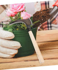 Portable Manganese Sickle For Weeding And Harvesting placed next to potted flower, showing ergonomic design and lightweight build.
