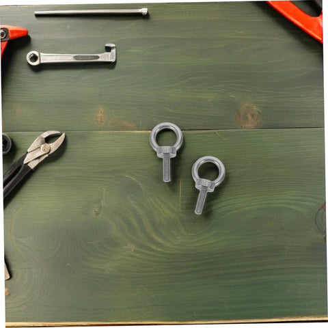 M6x20 Stainless Steel Eyebolts With Closed Ring And Hole For Concrete Anchoring, Beefy Heavy Duty Eye Screws With Nylon Nuts For Vibration Dampening, Super Secure Mounting For Hooks, Decor, And Industrial Projects. Two M6 stainless steel eyebolts on a green workbench.