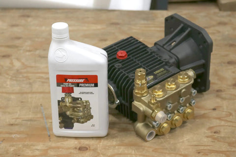 Premium Pump Oil For Pressure Washers 1 Liter Non Detergent Non Foaming Formula Delivers Strong Rust And Oxidation Protection With Easy Fill Neck Great Choice For Gas Powered Washers next to pressure washer pump on wooden table