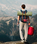 Hiker with red NOAA Weather Radio With Battery Backup And Solar Hand Crank, AM FM Shortwave Receiver in backpack, overlooking mountains