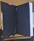 Open leather-bound edition of Must Have Loader And Scoop Type Parts Manual with visible spine and bookmark, standing on a wooden stand.