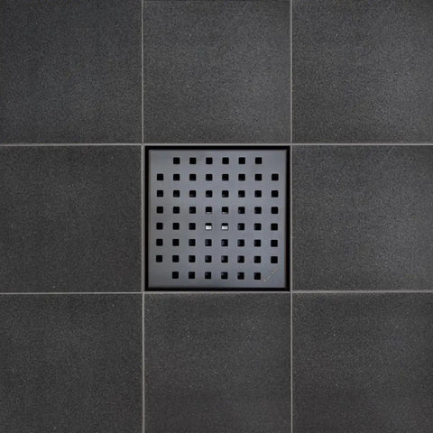 Premium 6 Inch Square Shower Drain With Slick Matte Black Polish And Heavy Duty 304 Stainless Steel Frame Built For Tile Bathrooms Featuring Reliable Hair Catcher Insert Hassle Free Setup Kit on black tile floor.