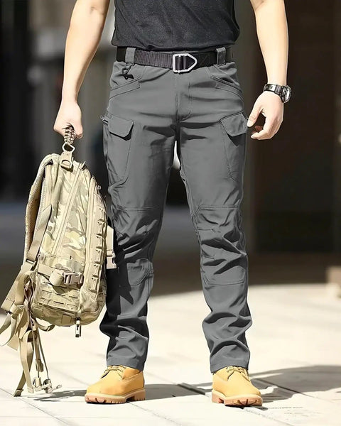 Mens Tactical Cargo Pants With Stretch Waterproof Fabric Durable Hiking And Work Pants Multi Pocket Cargo Breathable Abrasion Resistant Outdoor Gear No Belt Dark Gray worn by a person holding a backpack.