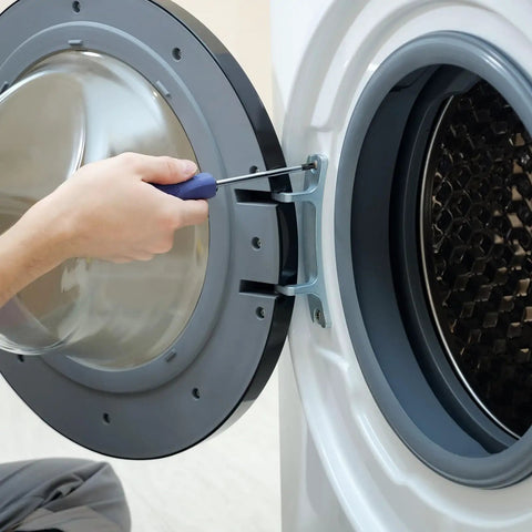 Hand using a screwdriver on a washing machine door hinge during assembly or repair.