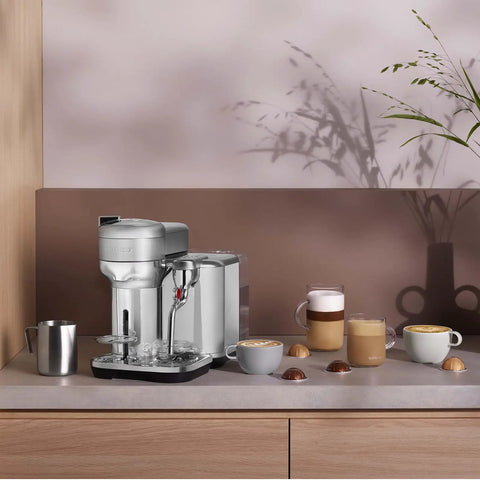 Vertuo Creatista Coffee And Espresso Maker By Breville For Pro Grade Home Barista Quality Brew 5 8 12 And 18 Oz Coffees Or Single And Double Espressos Hot Or Iced Features Barista Steam Wand For Latte Art Brushed Stainless Steel on counter with cups and capsules