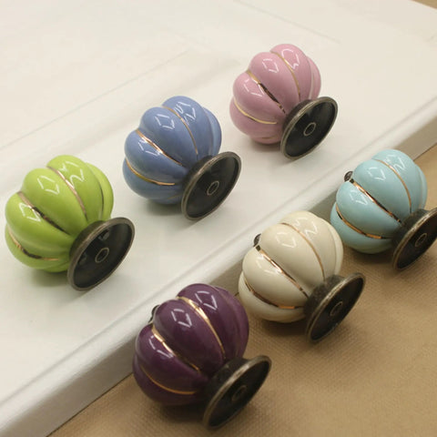 Super Slick Vintage Ceramic Pumpkin Cabinet Knobs 6 Piece Set in assorted colors on a surface, showcasing stylish drawer pulls for cabinets.