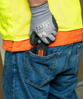 Person with glove holding tool in back pocket wearing workwear