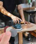 Person using Grab These Awesome Parliky 180 Sheet Round Hook And Loop Sanding Discs for woodworking on a power sander.