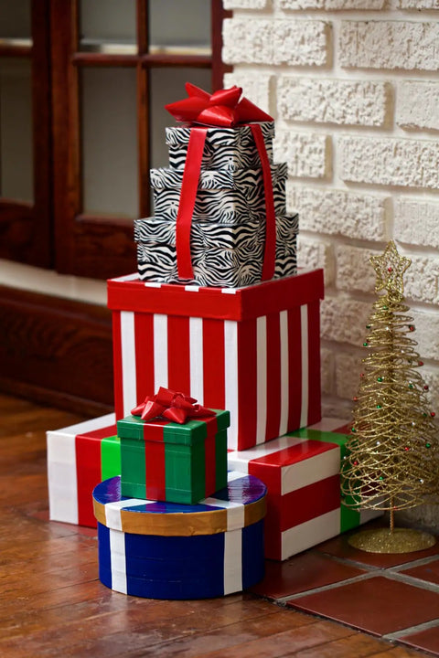 Holiday gifts stacked near a fireplace, wrapped with various colors, featuring Printed Duct Tape Checker Pattern 1.88 Inch Wide 10 Yard Roll.