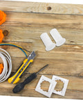 Premium Silicone Antenna Protectors And Wall Hole Plugs For Seamless Drywall Cable Routing. White silicone grommets with cable, tool, and wall plates on wood.