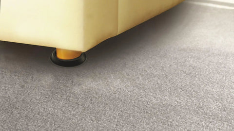 Slick Polyethylene Furniture Sliders Made To Fit Round Table And Sofa Legs under a sofa leg on a smooth gray surface.