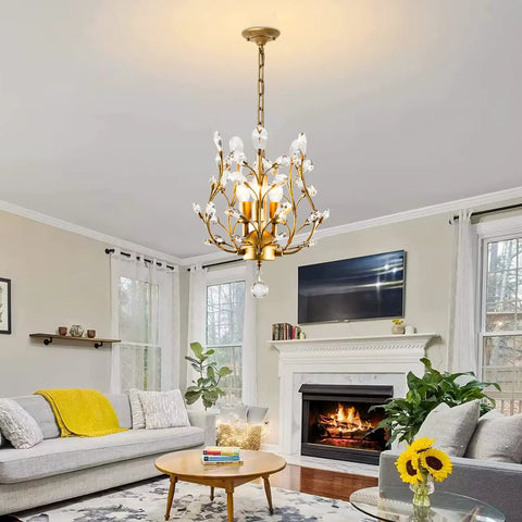 Three Light K9 Crystal Pendant Chandelier In Gold hanging in a modern living room setting with sofa and fireplace.