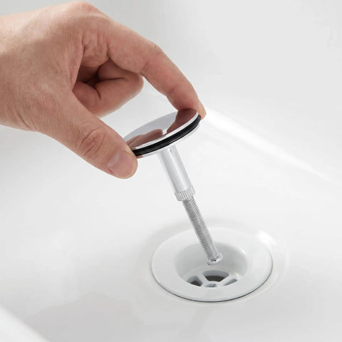 Hand holding Rotary Bath Tub Plug Drain Stopper for Bathtub Overflow Cover above a bathtub drain for easy installation.