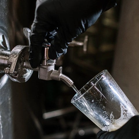 Close-up of DERNORD stainless beer sampling valve with 1.5-inch tri-clamp end dispensing beer into a glass.