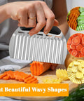 Front view of Nogeqi stainless steel crinkle cutter with black handle slicing carrots into wavy pieces on a board