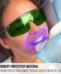 Person wearing Laser Safety Glasses For IPL 200 To 2000 Nm Eye Protection For Laser Hair Removal And Engraving UV400 Blocking OD4 Plus Fifteen Percent Visible Light Transmission Broad Spectrum Shield PC Material Comfy Fit Green Lens during dental procedure