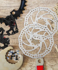 Heavy Duty Mechanical Disc Brake Kit With Front And Rear Rotors And Thick Pads For Mountain Bike on wooden surface, showing rotors and calipers.