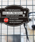 2 Pack No Trespassing And Dog On Premises Yard Signs, 10 By 7 Inch Rock Solid Aluminum Warning Plates displayed on a fence with a dog behind.