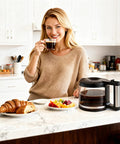 Glass 10-cup coffee carafe replacement for De'Longhi coffee maker with black lid on kitchen counter.