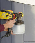Person using iSpray Front End Nozzle For HVLP Sprayers Broad Interior And Exterior Coverage With Unthinned Coatings on blue wall