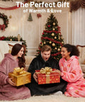 Three people wearing wearable blanket hoodie for adults with flannel and sherpa lining around a Christmas tree, holding gifts.