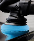 Close-up of a Color Coded Pro Grade Waffle Foam Buffing Pad attached to polisher, showing blue pad buffing a car surface.