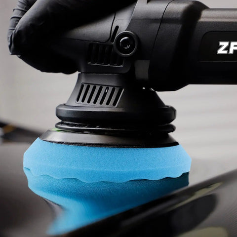Close-up of a Color Coded Pro Grade Waffle Foam Buffing Pad attached to polisher, showing blue pad buffing a car surface.