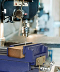 Badass Six Inch Cross Slide Drill Press Vise with wood being drilled in heavy duty bench vice setup.