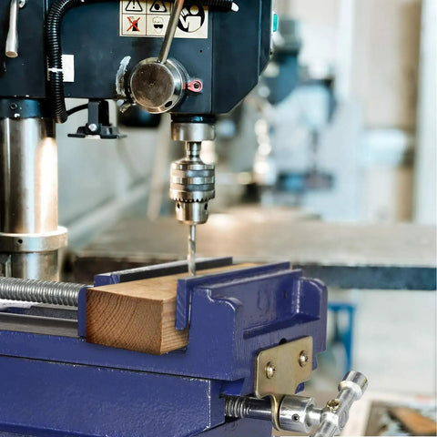 Badass Six Inch Cross Slide Drill Press Vise with wood being drilled in heavy duty bench vice setup.
