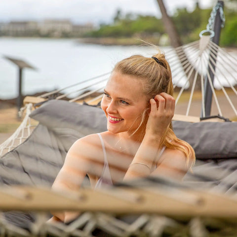 Woman relaxing on Two Person Outdoor Hammock With Stand And Carry Bag, Cotton Rope Hammock With Detachable Reversible Quilted Pad, Dark Gray.
