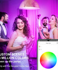 People dancing under Bright 1050 Lumen Smart RGB LED Bulbs with phone showing color changing feature, creating lively atmosphere.