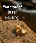 Glow In The Dark Brass Pocket Compass For Kids, Waterproof Navigation Tool on a rock highlighting brass housing.
