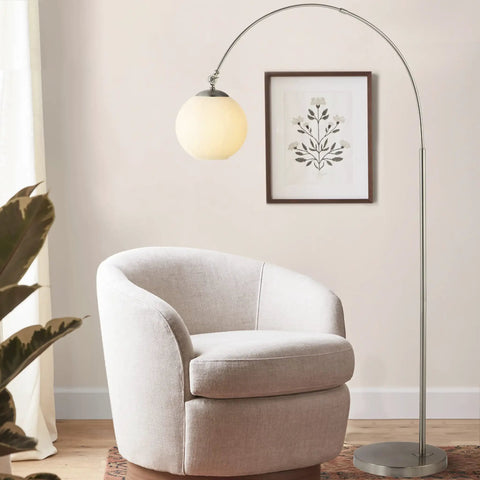 Nickel And White Nora Arc Floor Lamp With Mercury Glass Shade next to a modern armchair in living room setting