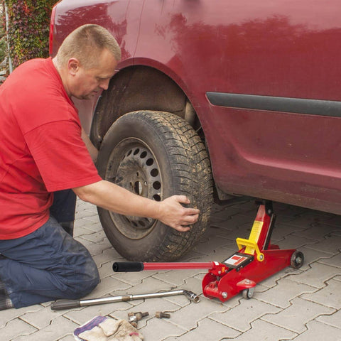Man using lightweight 2 ton floor jack with carbon steel handle to lift car for tire change