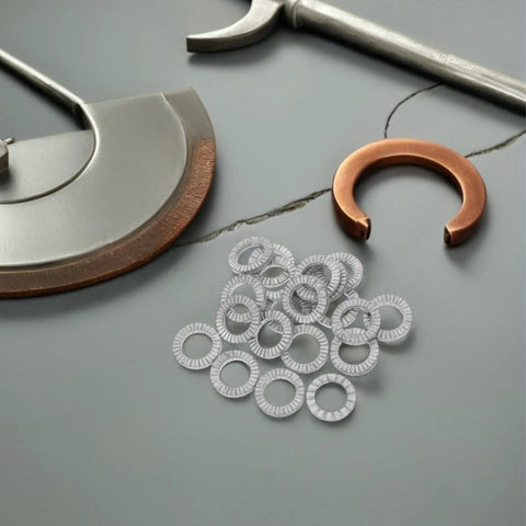 30 Pair M10 Double Layer Self Locking Wedge Shaped Anti Vibration Safety Washers Built From Heavy Manganese Steel on a workspace.