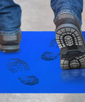 Person walking on Heavy Duty Tear Away Sticky Adhesive Floor Mats 36 By 18 Inch Grit Eater with footprints visible.
