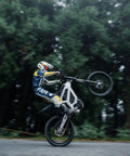 Adult Off Road Electric Dirt Bike Featuring A Badass 16800W Peak Motor And Massive 72V 50Ah Battery For Serious Torque Beast Mode Riding, performing a wheelie on a forest path.