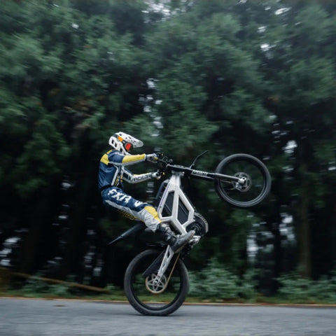 Adult Off Road Electric Dirt Bike Featuring A Badass 16800W Peak Motor And Massive 72V 50Ah Battery For Serious Torque Beast Mode Riding, performing a wheelie on a forest path.