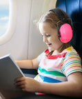 Child wearing pink earmuffs, part of 9 Pack Kids Earmuffs For Noise Reduction 29dB Adjustable Fit Ear Protection, reading on airplane.