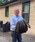 Man holding Heavy Duty Garden Hose With Female To Female Connectors, 6 Feet By 5/8 Inch Black Water Hose for garden use.