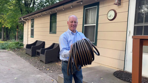 Man holding Heavy Duty Garden Hose With Female To Female Connectors, 6 Feet By 5/8 Inch Black Water Hose for garden use.