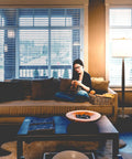 Lucas LED Floor Lamp With Drum Shade And Warm Wood Finish beside sofa in living room setting, creating ambient lighting.
