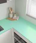 Thick Pastel Mint Metallic Peel And Stick Wallpaper With Brushed Matte Surface Gives Your Space A Straight Up Glow Up Self Adhesive Removable Backsplash For Quick DIY Upgrades on a kitchen countertop.