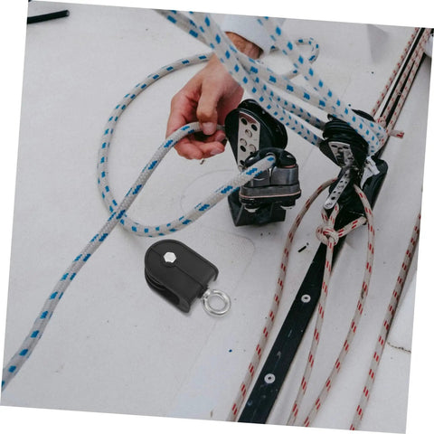 Heavy Duty Pulley Block Built Tough With Silent Rotating Wheel For DIY Home Gym Cable Systems Swivel Lifting Pulleys That Run Smooth Detachable Roller Wheel For Easy Setup And Smooth Operation. Black pulley block with rope on workbench