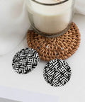Black And White Grid Print Dangle Earrings For Women, Hella Lightweight Faux PVC Leather Look With Secure Silver Plated Hooks on a table with a candle.
