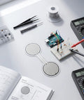 Heavy Duty Force Sensing Resistor With A No Stress Setup For 0 To 30 Kilograms Of Pressure Mapping and Snappy Analog Response On The 30 Mm Round Pad. Prototyping setup on a workbench.